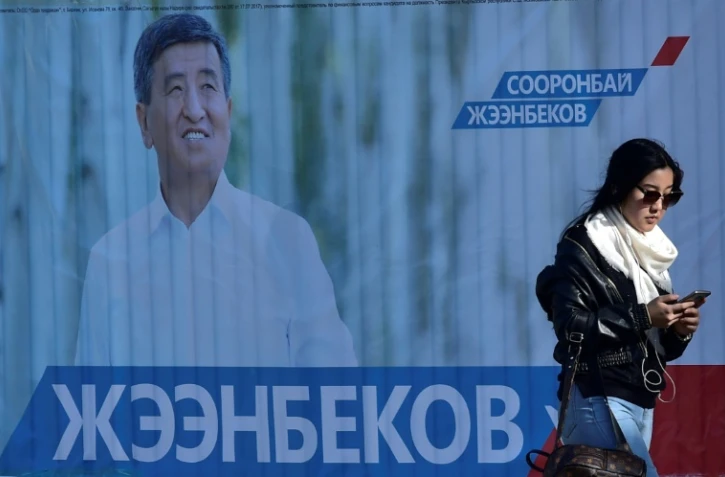 Une femme passe devant une affiche de campagne du candidat à l'élection présidentielle Sooronbai Jeenbekov, à Bishkek au Kirghizstan, le 12 octobre 2017