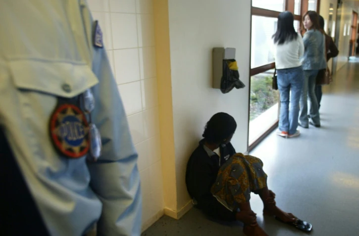 Des personnes sous la surveillance d'un policier, le 27 octobre 2003 dans le centre de rétention de la zone d'attente de l'aéroport de Roissy-Charles de Gaulle