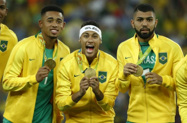 L'international brésilien Neymar au milieu de deux coéquipiers, célèbre la médaille d'or de son pays aux Jeux de Rio, avec un bandeau "100% Jésus", le 20 août 2016 à Rio de Janeiro