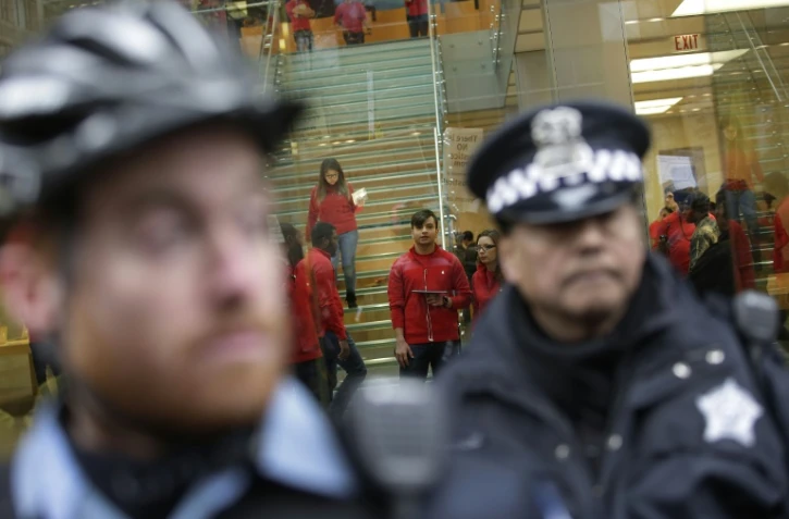 Un policier bloque l'entrée d'un magasin à Chicago, le 24 décembre 2015 lors d'une manifestation contre les violences policières