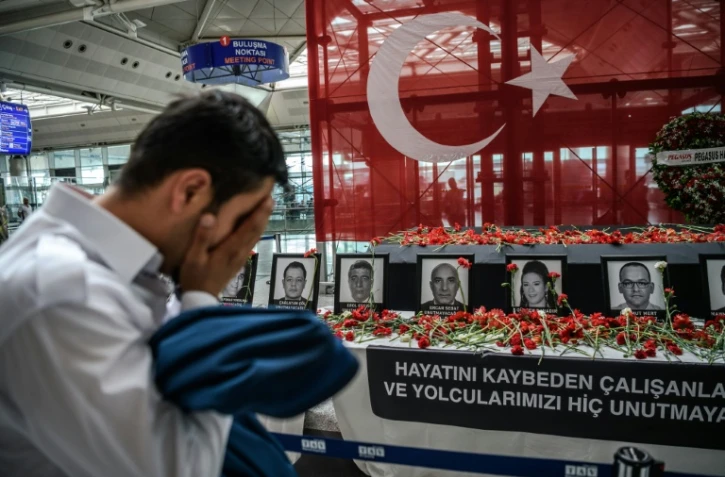 Un employé de l'aéroport se recueille devant un autel en hommage aux victimes des attentats, à l'aéroport Atatürk d'Istanbul