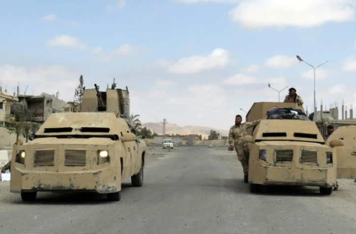 Des membres des forces syriennes dans des blindés à Palmyre, le 27 mars 2016 