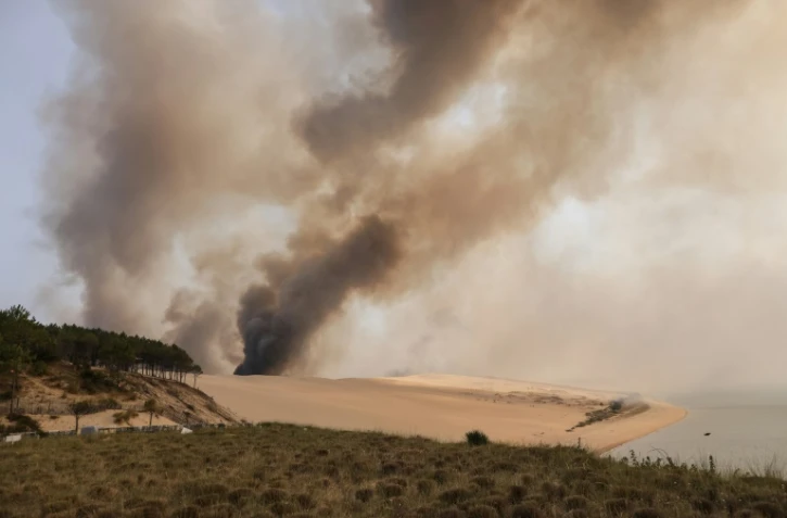 De la fumée s'élève de l'incendie qui ravage la forêt de pins en contrebas de la dune du Pyla, en Gironde, le 18 juillet 2022