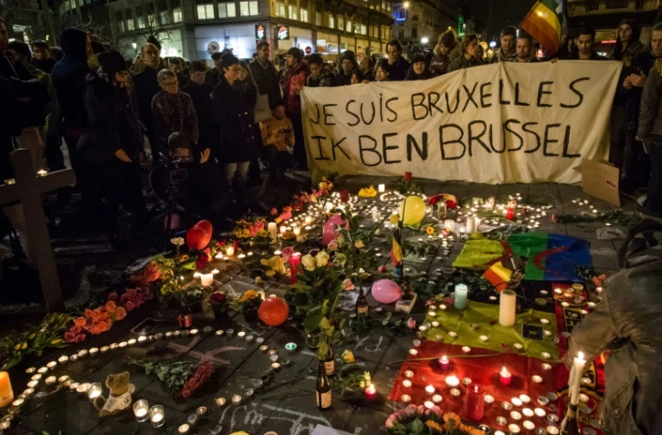 Des personnes rassemblées place de la Bourse à Bruxelles, le 22 mars 2016, devant un parterre de bougies, de fleurs et de messages en hommage aux victimes des attentats