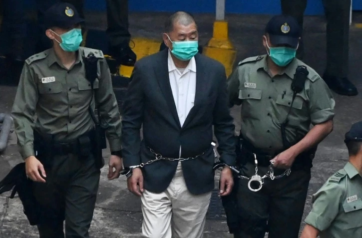 Le magnat pro-démocratie Jimmy Lai (C), accusé d'atteinte à la sécurité nationale, est accompagné par des policiers vers le tribunal le 12 décembre 2020 à Hong Kong