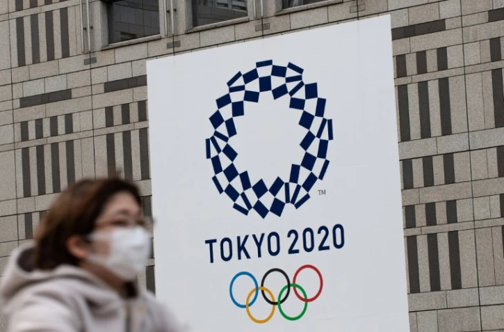 Une femme portant un masque passe devant le logo des Jeux olympiques de Tokyo, le 23 avril 2020