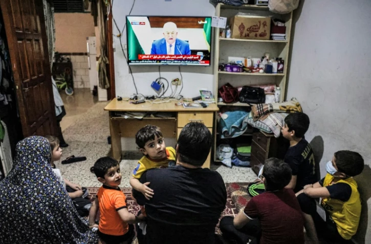 Une famille palestinienne assiste au discours du président de l'Autorité palestinienne Mahmoud Abbas à la télévision, à Rafah (Territoires palestiniens), le 29 avril 2021