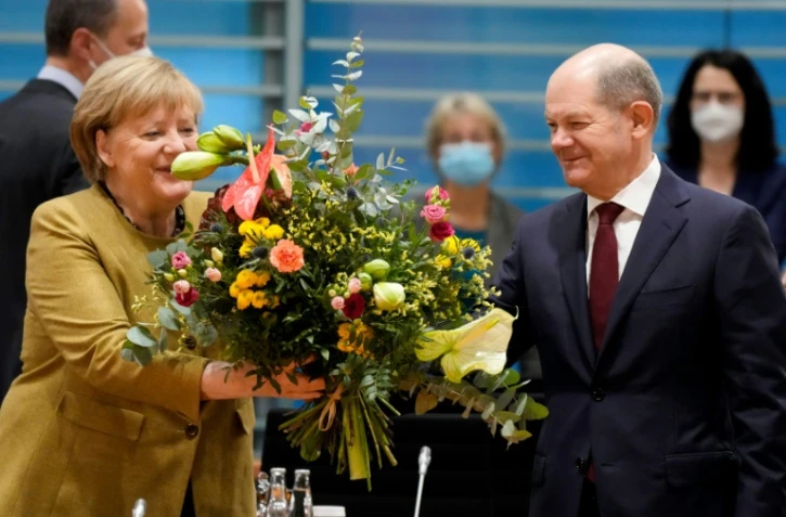 La chancelière allemande Angela Merkel reçoit un bouquet de fleurs d'Olaf Scholz (d), candidat du parti social-démocrate à la chancellerie, le 24 novembre 2021 à Berlin