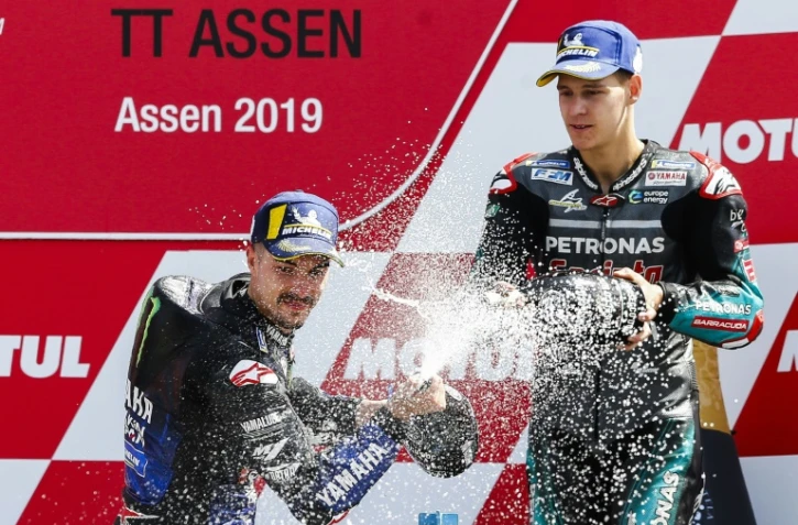 L'Espagnol Maverick Vinales (g), vainqueur du GP des Pays-Bas, sabre le champagne au côté du Français Fabio Quartararo, 3e, sur le circuit d'Assen, le 30 juin 2019