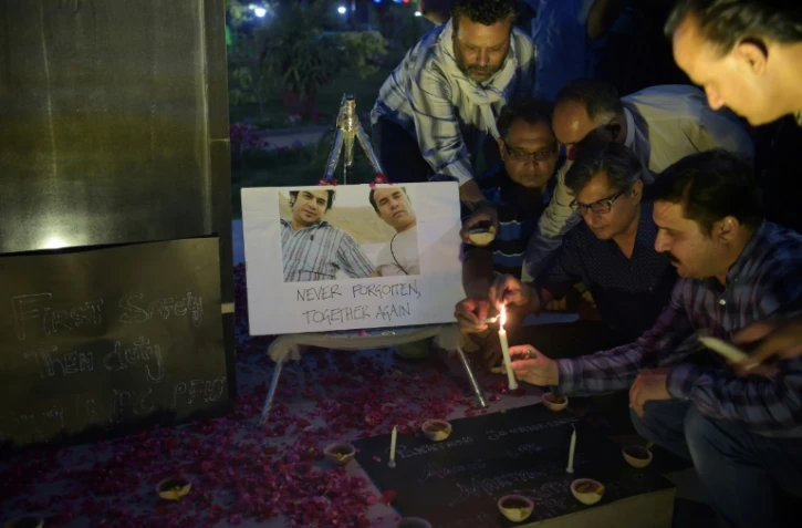 Des journalistes se recueillent mercredi 3 mai devant une photo de Shah Marai et de Sardar Ahmad, deux reporters de l'AFP tués en Afghanistan.