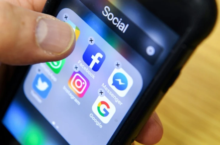 Un homme tient un smartphone sur lequel on voit des icones dont celui de l'application Facebook, à Moscou le 23 mars 2018