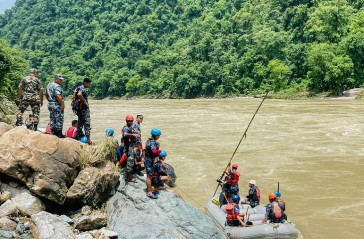 Des membres de la police armée recherchent des survivants dans la rivière Trishuli après un glissement de terrain qui a emporté deux bus, le 13 juillet 2024 à Simaltar, au Népal