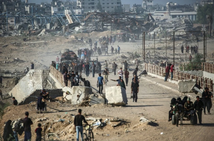 Des Palestiniens marchent le long de la route côtière dans le centre de la bande de Gaza en direction de la ville de Gaza, dans le nord, le 11 octobre 2025