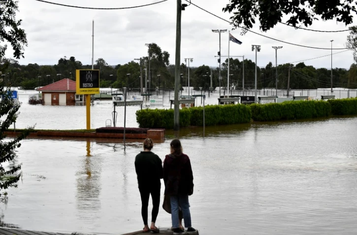 Des résidents regardent la montée des eaux de crue près de la zone commerciale dans la banlieue sud-ouest de Camden à Sydney, le 8 mars 2022
