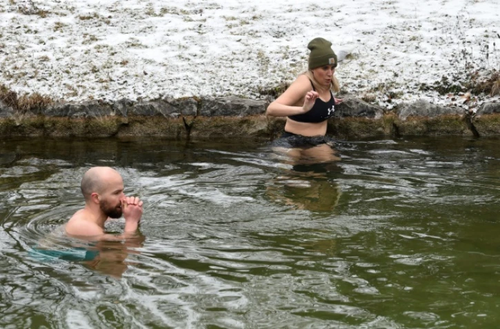 Erina Hey et Franz Mayr se glissent dans les eaux glaciales de la rivière Eisbach dans l'English Garden park de Munich, le 16 janvier 2021