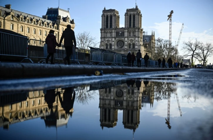 Des piétons longent des barrières de sécurité installées la veille de la réouverture officielle de la cathédrale Notre-Dame de Paris, le 6 décembre 2024 à Paris