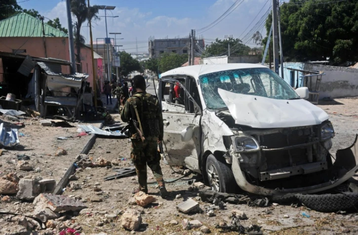 Un soldat près d'une voiture endommagée dans un attentat à la bombe, le 2 janvier 2017 à Mogadiscio, en Somalie
