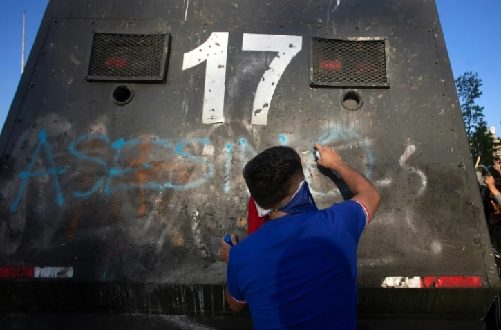 Un manifestant écrit "Assassins" sur un véhicule de la police lors d'une manifestation à Santiago du Chili le 3 novembre 2019