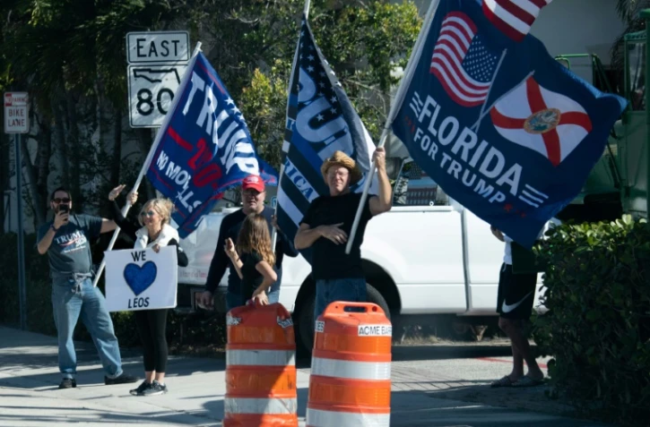 Des sympathisants du président américain Donald Trump saluent le passage du convoi présidentiel à West Palm Beach, en Floride, le 27 décembre 2020