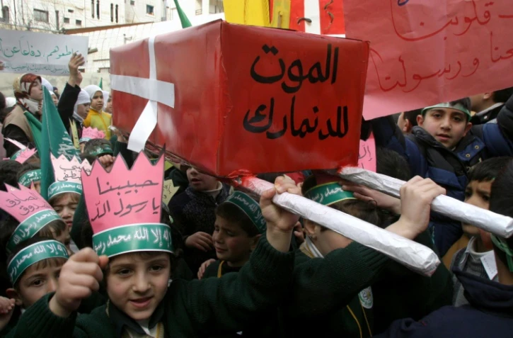 De jeunes Palestiniens défilent à Hébron, en Cisjordanie, le 13 février 2006 avec un faux cercueil ceint d'un drapeau danois sur lequel est inscrit "Mort au Danemark", en réaction à la parution en 2005 de caricatures de Mahomet dans un journal danois