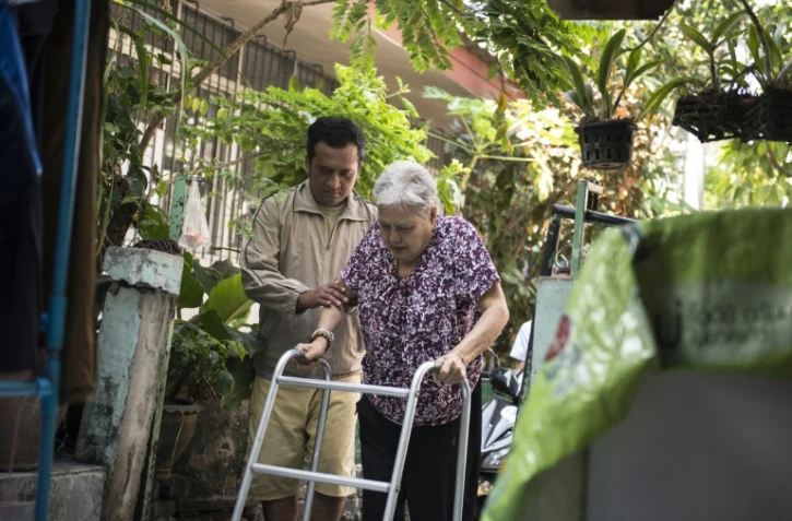 Nakhon Thianprasert (g) aide sa vieille tante de 77 ans  Boonrod Khamhomkul (d) à rentrer chez elle après une journée passée dans un centre de soins à Bangkok, le 3 mars 2016 