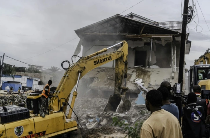Un engin de chantier démolit des maisons à Kinshasa,, après que les autorités de la RDC ont décidé de démolir tous les bâtiments non autorisés dans les zones inondables, le 8 mai 2025 en RDC