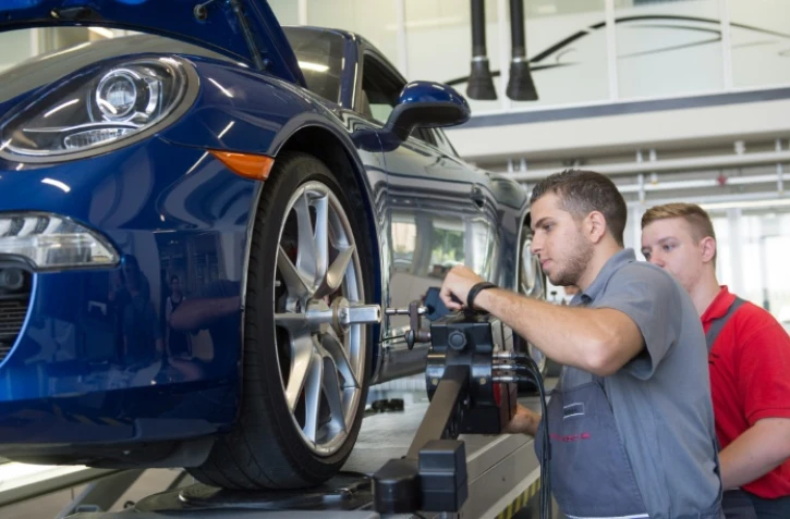 Ammar Alkhouli (g), réfugié de Syrie apprend avec son enseignant Dennis Strohmaier, la mécanique au centre de formation de Porsche à Stuttgart, le 27 juillet 2016