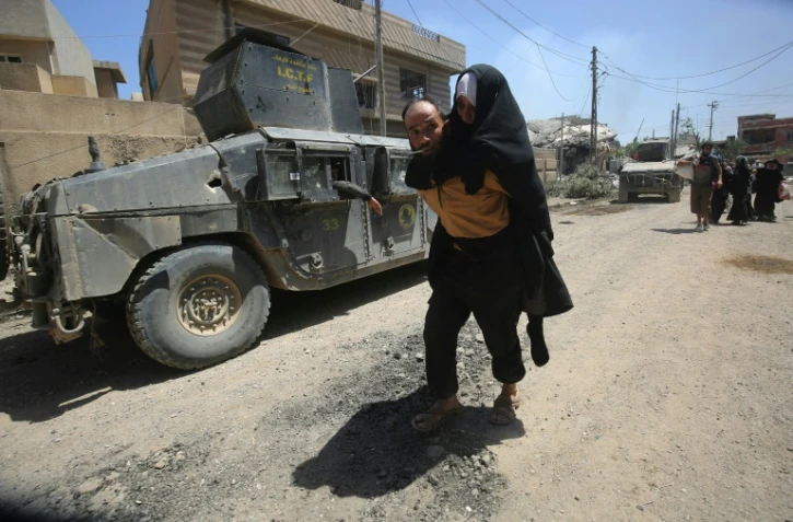 Un homme porte une femme sur son dos alors qu'ils fuient les combats entre les forces irakiennes et les jihadistes de l'EI, le 17 mai 2017 Ă Mossoul-Ouest