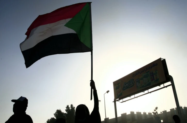 Un homme agite le drapeau soudanais lors d'une manifestation pour réclamer le retour du pouvoir civil, le 13 décembre 2021 près de Khartoum