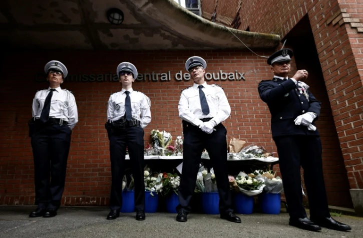 Des policiers se tiennent près d'un mémorial improvisé en hommage aux trois policiers tués le 21 mai devant un commissariat de Roubaix, dans le nord de la France, le 23 mai 2023