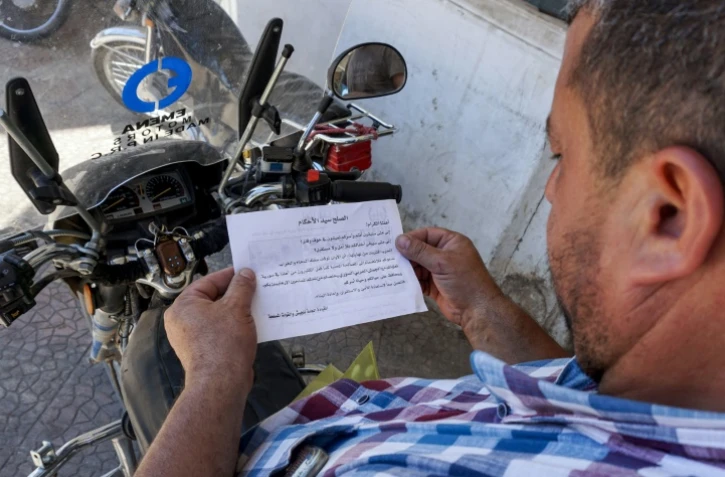 Un Syrien lit un tract portant le sceau des forces gouvernementales et appelant la population à "rejoindre le (processus de) réconciliation" à Binnish, dans le nord-ouest de la Syrie, le 9 août 2018