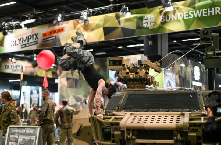 Un visiteur fait le poirier sur un véhicule de l'armée allemande, sur le stand de la Bundeswehr, au plus grand salon mondial du fitness, la Fibo, à Cologne (ouest de l'Allemagne), le 16 avril 