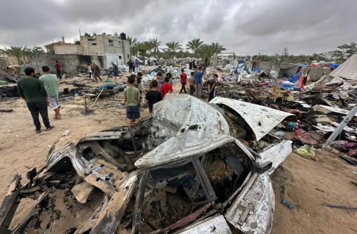 Des Palestiniens au milieu des dégâts dans le camp de déplacés à Al-Mawassi visé par des frappes israéliennes, dans le sud de la bande de Gaza, le 18 mai 2025
