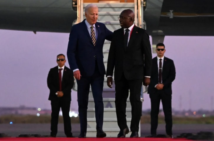 Le président américain Joe Biden (g) marche à côté du ministre angolais des Affaires étrangères Tete Antonio à son arrivée à l'aéroport international Quatro de Fevereiro de Luanda, le 2 décembre 2024