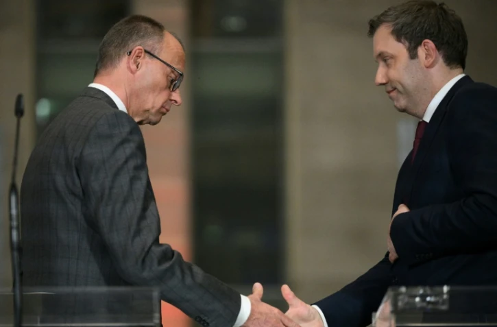 Le chef de l'Union chrétienne-démocrate (CDU) d'Allemagne, Friedrich Merz, et le co-président du Parti social-démocrate allemand (SPD) Lars Klingbeil se serrent la main après une conférence de presse sur les investissements majeurs prévus, à Berlin, le 4 mars 2025
