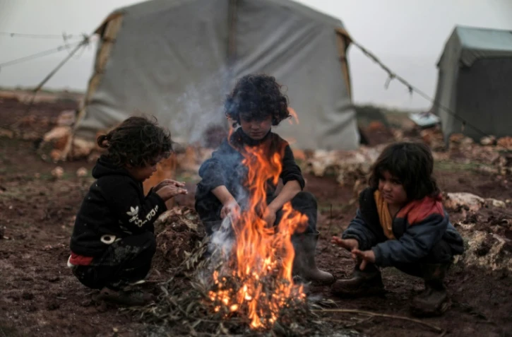 Des enfants autour d'un feu dans un camp de déplacés, dans le nord-ouest de la Syrie, le 17 décembre 2021