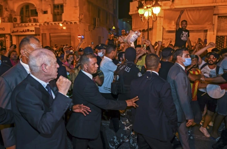 Une photo fournie par la présidence tunisienne montre le chef de l'Etat Kais Saied (G) levant le poing droit pour célébrer avec ses partisans à Tunis la victoire quasi certaine du "oui" au référendum sur une Constitution contestée, le 26 juillet 2022