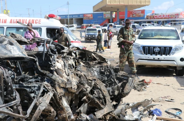 Un soldat se tient près de la carcasse d'une voiture détruite par un attentat qu a fait au moins 76 morts le 28 décembre 2019 à Mogadiscio.