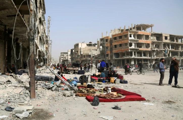 Des civils rassemblent leurs biens dans les rues d'Arbine, dans la Ghouta orientale, dans l'attente de leur évacuation vers le nord-ouest de la Syrie, le 27 mars 2018