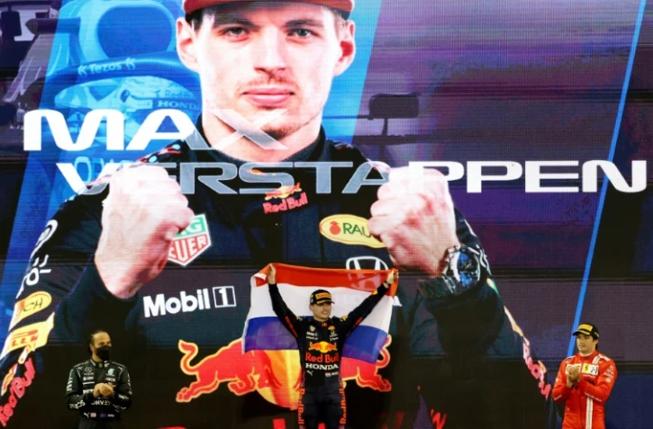 La joie sur le podium du pilote néerlandais Max Verstappen, après avoir remporté le Grand Prix d'Abou Dhabi et décroché son 1er titre mondial, le 12 décembre 2021, devant le septuple champion du monde, le Britannique Lewis Hamilton (g) et l'Espagnol Carlos Sainz Jr