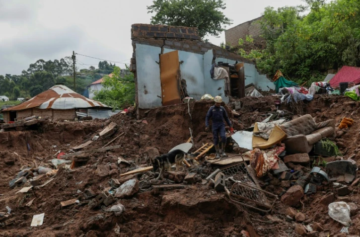 Un secouriste sud-africain explore les décombres avec un chien le 15 avril 2022 près de Durban en Afrique du Sud, après les inondations et glissements de terrain provoqués par de fortes pluies dans l'est de l'Afrique du Sud