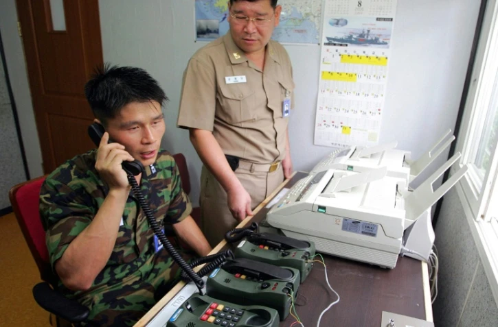 Photo d'archives prise le 10 août 2005 montrant le lieutenant sud-coréen Choi Don-Rim (G) communiquant avec un officier nord-coréen durant un appel téléphonique depuis un bureau militaire près de la Zone démilitarisée séparant les deux Corées