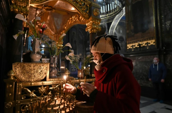 Une fidèle allume un cierge dans la cathédrale orthodoxe Saint Volodymyr presque déserte à Kiev le 18 avril 2020