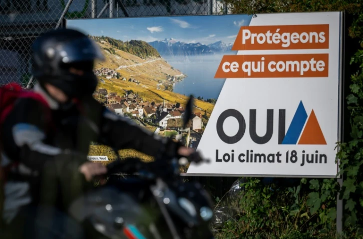 Un motard passe devant une affiche électorale indiquant "Protégeons ce qui compte, OUI, loi climat 18 juin" à Lausanne, en Suisse, le 14 juin 2023
