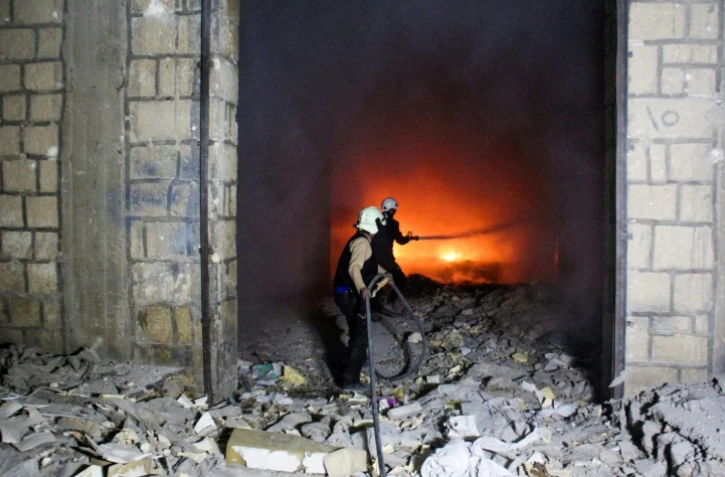 Des Casques blancs, une organisation de secouristes en zone rebelle, luttent contre un incendie après des frappes aériennes sur la ville d'Idleb, le 24 mars 2017 en Syrie