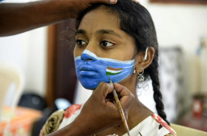 Un artiste peint un masque sur le visage d'une jeune fille lors d'une campagne de sensibilisation au Covid-19 à Hyderabad (Inde) le 20 septembre 2020