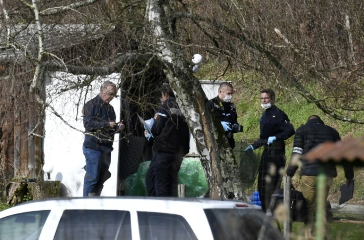 Des gendarmes et des experts en médecine légale fouillent une cabane de jardin le long d'une route près de Domessin dans l'est de la Savoie le 14 février 2018