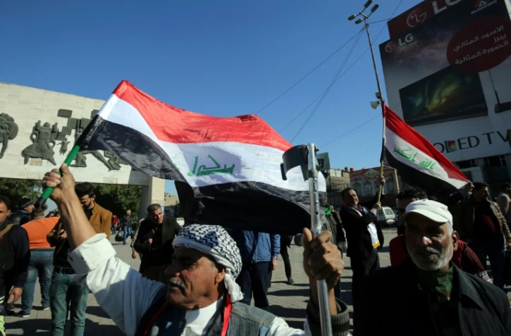 Des Irakiens brandissent le drapeau national lors de la parade militaire pour célébrer la victoire militaire contre le groupe Etat islamique (EI), à Bagdad