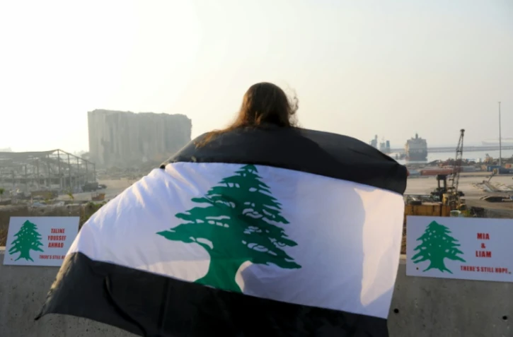 Une femme enveloppée dans un drapeau libanais bordé de noir manifeste à Beyrouth, le 6 septembre 2020 un mois après l'explosion meurtrière