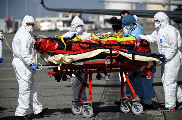 Le personnel médical transporte un patient infecté par le Covid-19 qui a été transféré de Nice, où les unités de soins intensifs sont surchargées, le 16 mars 2021 à Toulouse-Blagnac